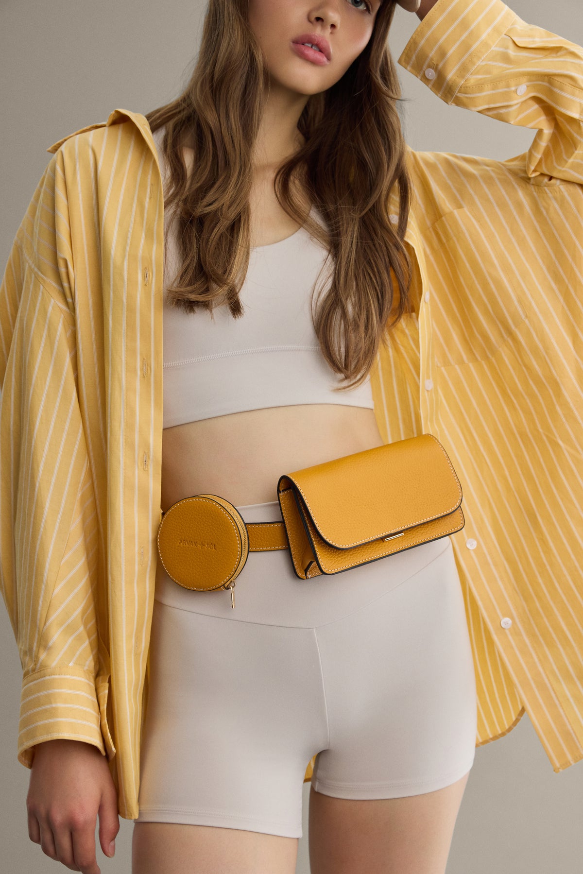 Mini Flap Bag by Arvak + Sól featuring a sleek design with a fold-over flap and adjustable strap, shown in a neutral color.